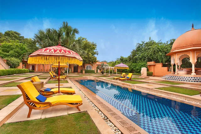chairs next to pool at the oberoi raj vilas hotel in jaipur, rajasthan