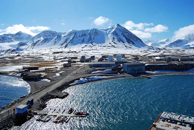 snow capped hill under clear sky in ny alesund city in svalbard, norway