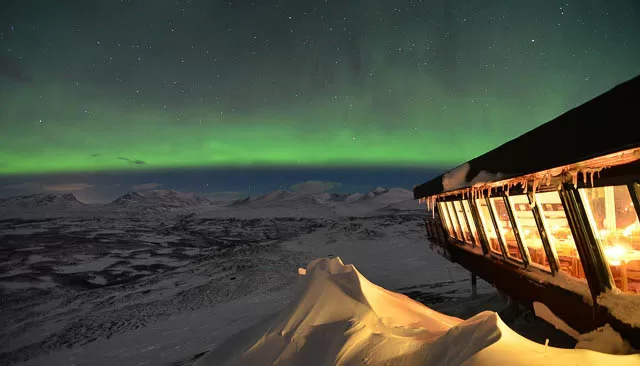 northern lights in front of aurora sky station in abisko, sweden