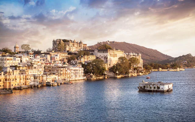 lake pichola with city palace view at cloudy sunset sky in udaipur, rajasthan