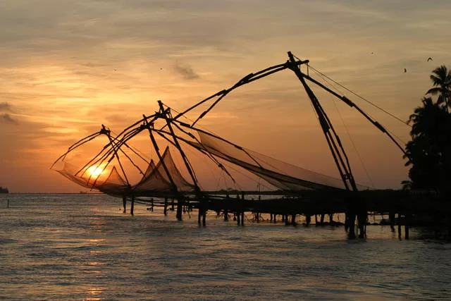 chinese fishing nets catching glimpse of sunset in cochin, kerala