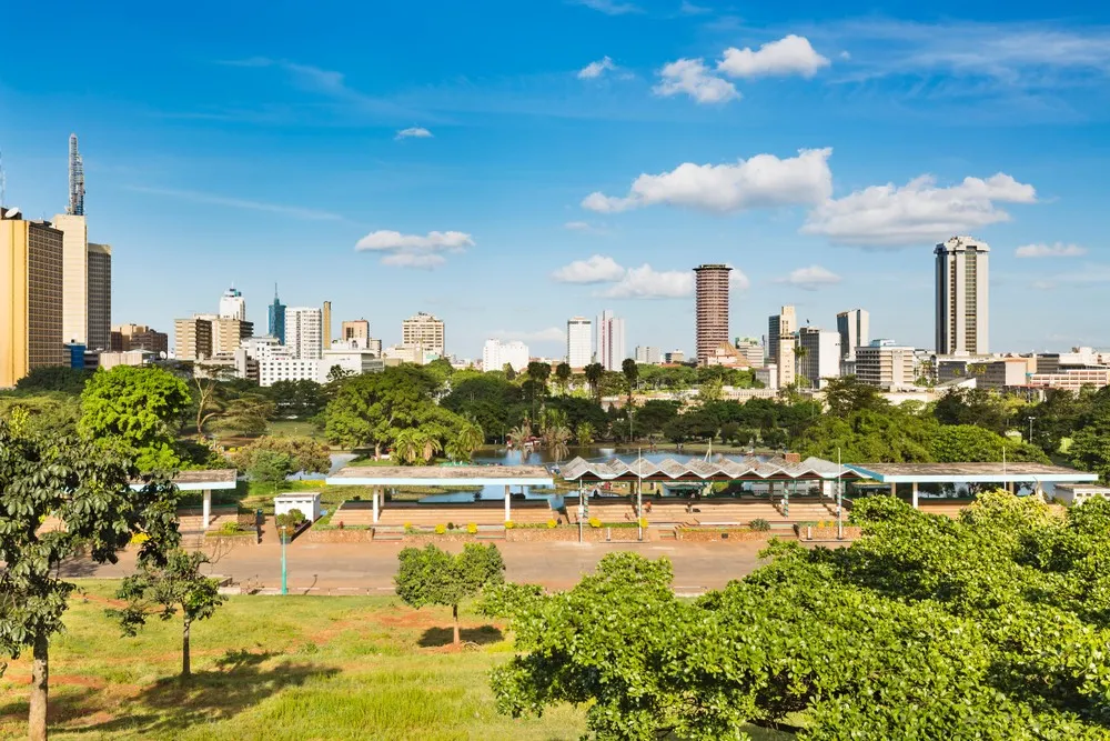 Lions resting on the plains of Nairobi National Park, skyscrapers on the horizon.