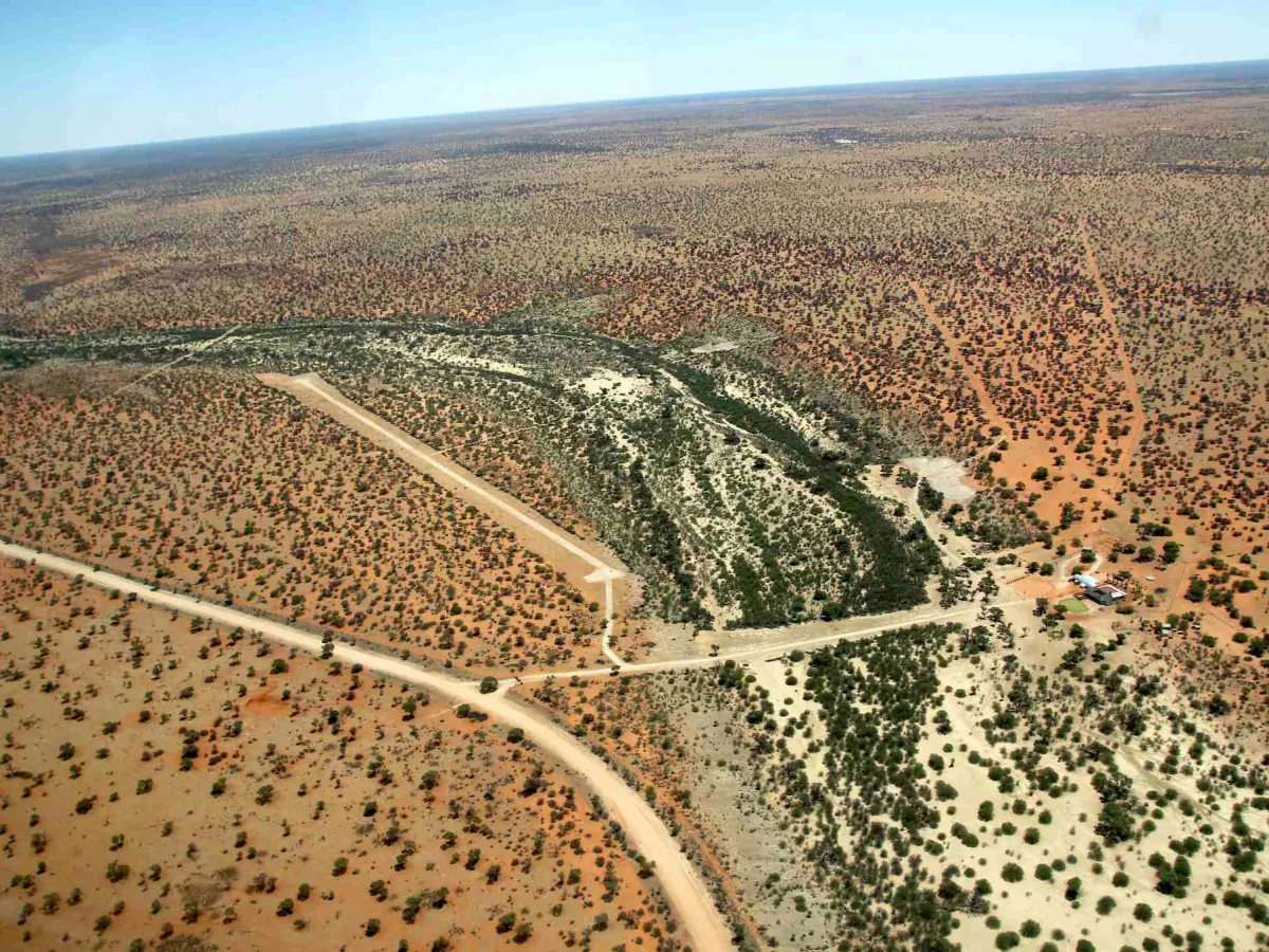 The dry Nossob riverbed winding between red Kalahari dunes.