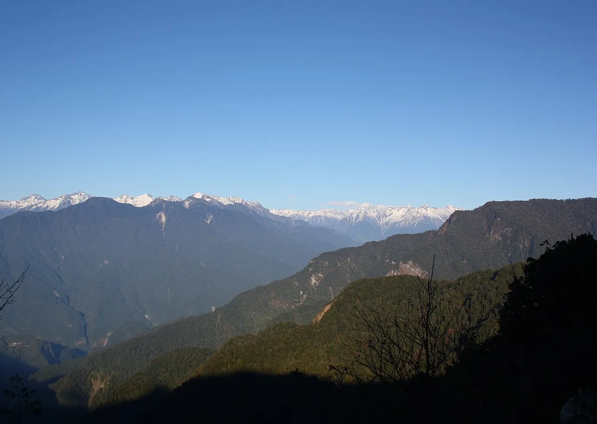 Forested Mishmi ridges rising in layers into Himalayan cloud.