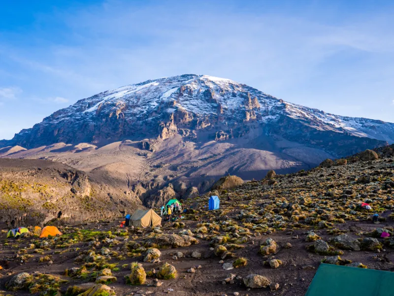 Trekkers crossing the high alpine desert with the glaciered summit ahead.